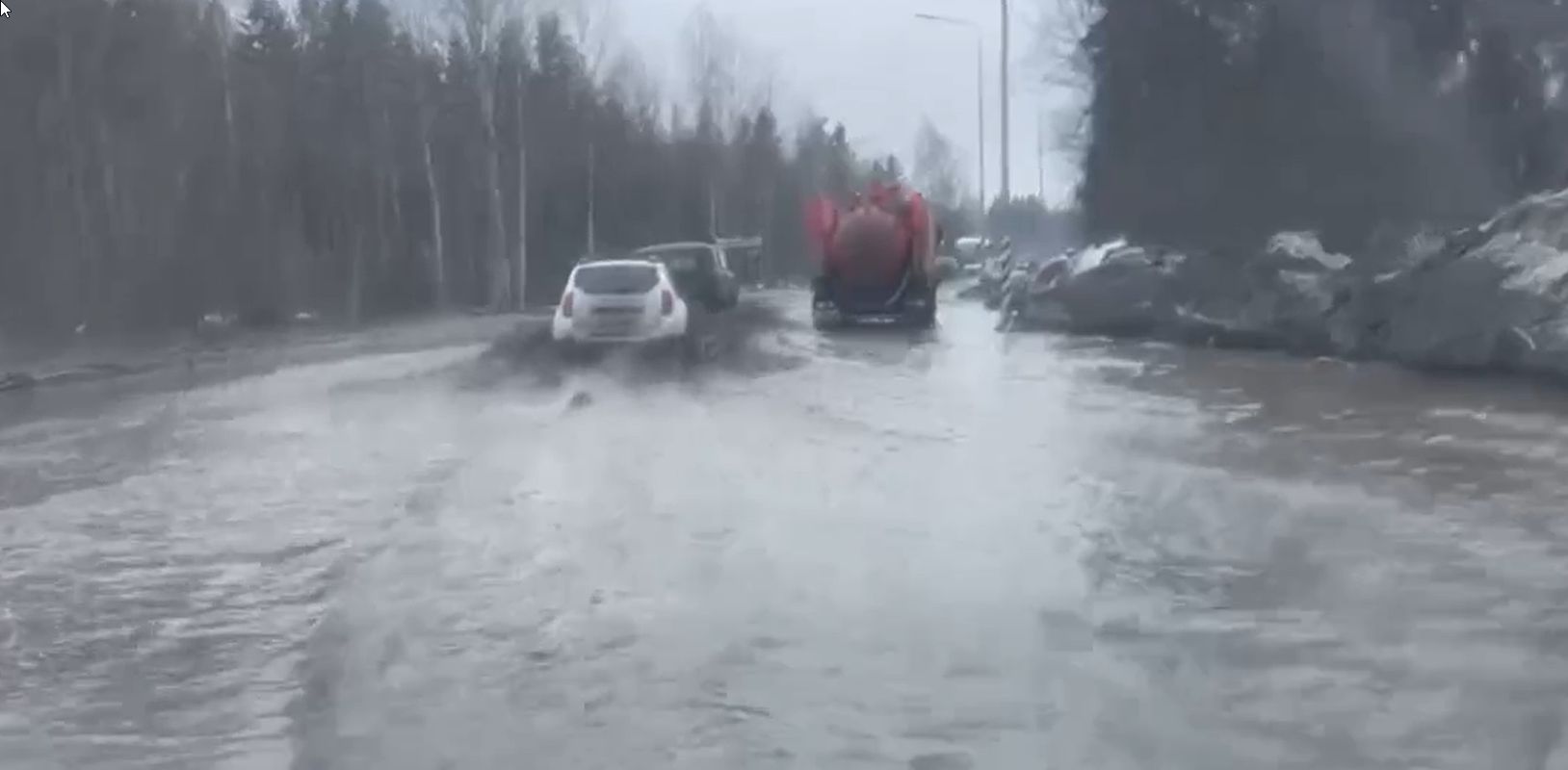 На выезде из Петрозаводска нужна лодка: машины едва выплывают из озера на дороге