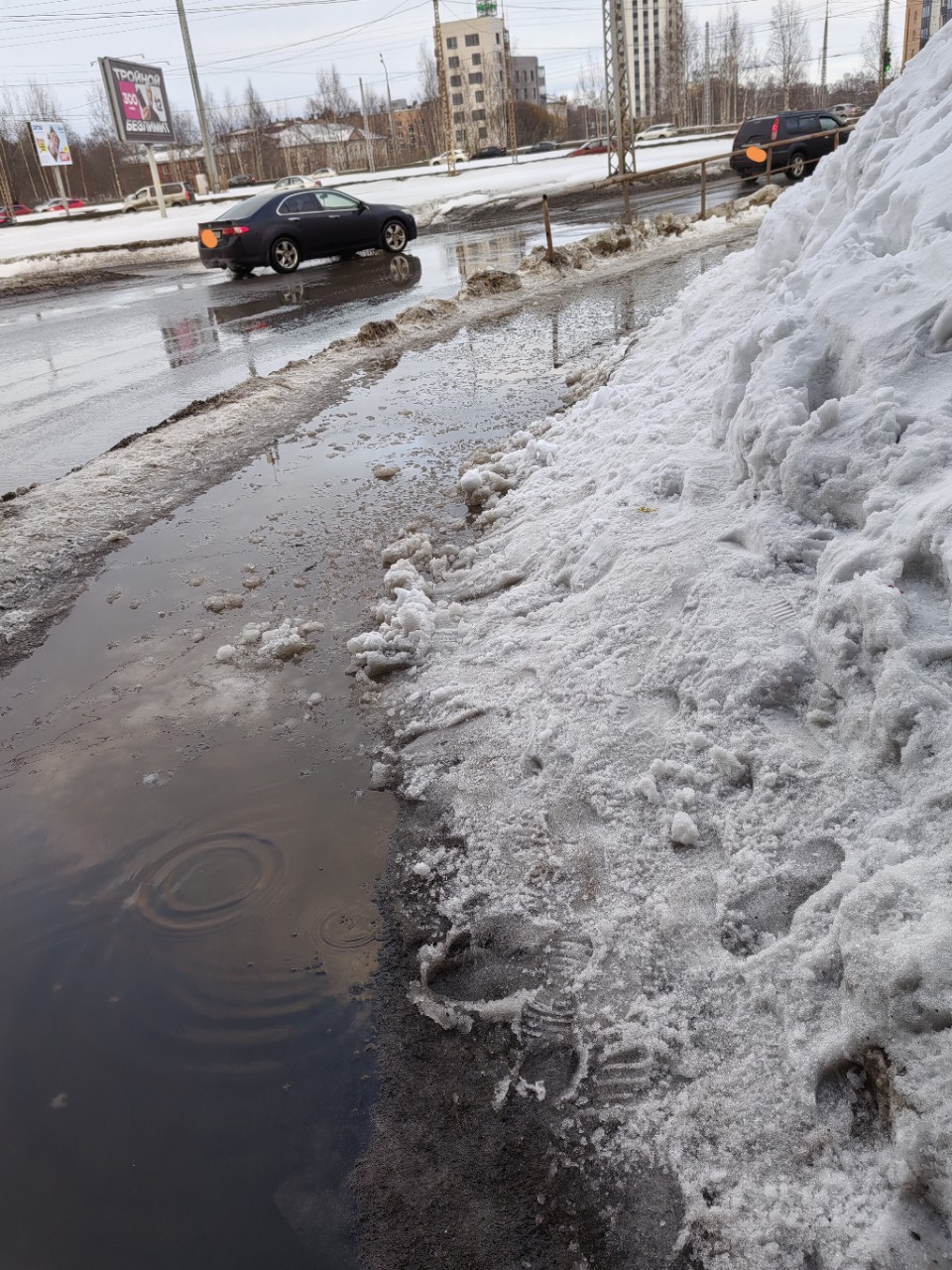 Одна из вечных луж в Петрозаводске вынуждает горожан делать пируэты с риском окунуться